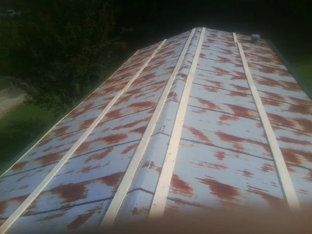 Rusted metal roof panels with new wood purlins before replacement — Storm Damage Roof Repair in East Kingston by Roofing Brothers