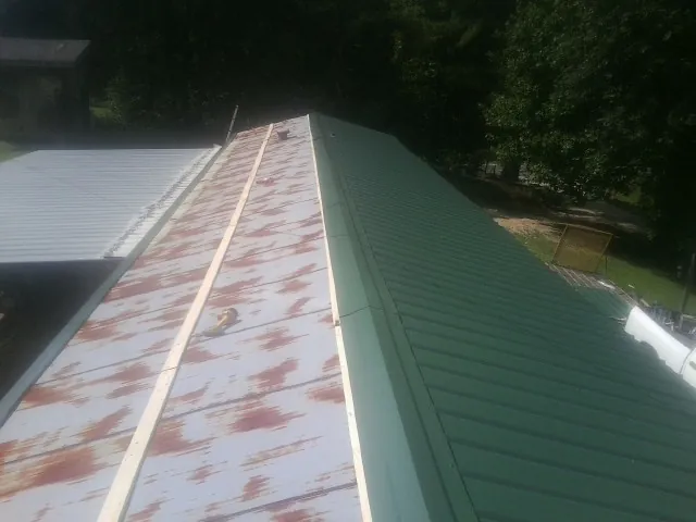 Old rusted panels beside newly installed green metal roofing — Wind Damage Roof Repair by Roofing Brothers in East Kingston