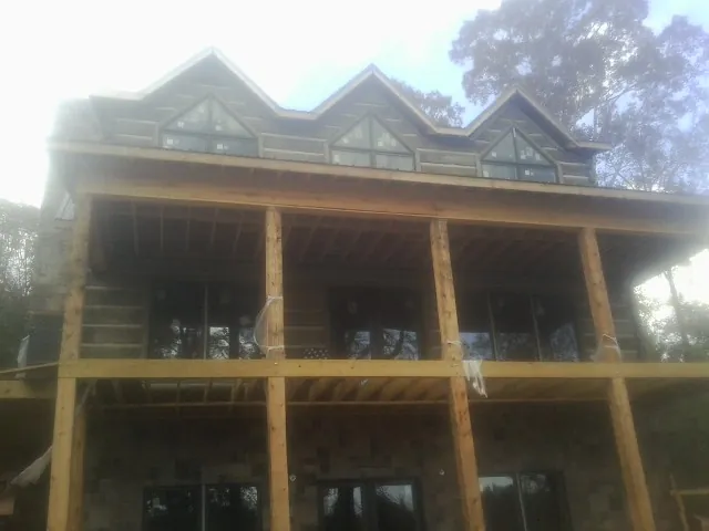 Dormers and porch framing on a large log home under construction — Roof Coating work by our crew in East Kingston