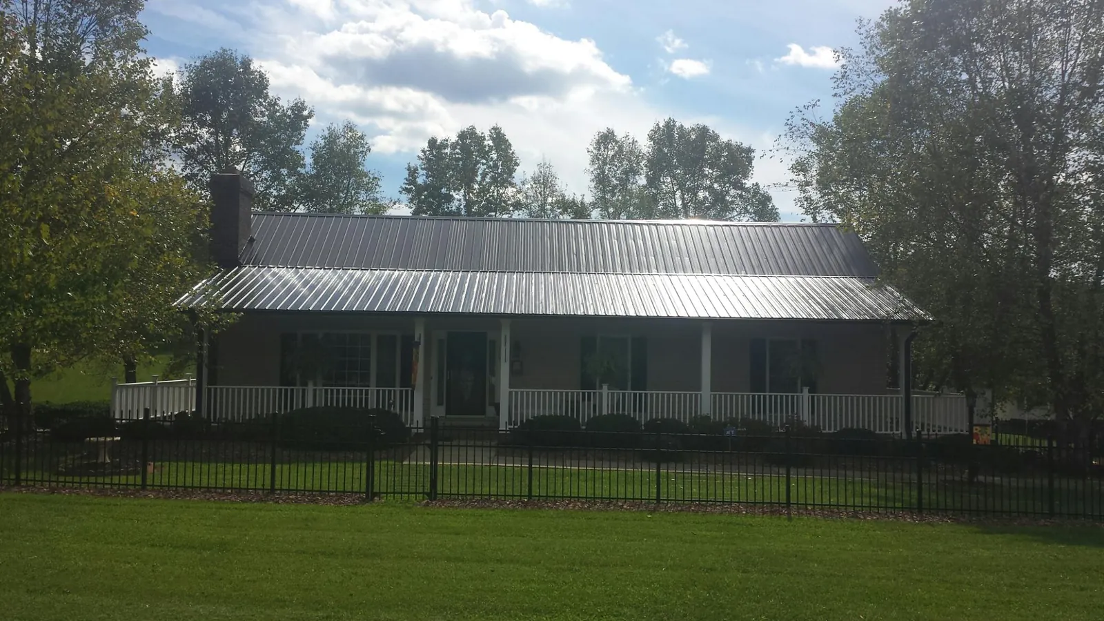 Gray metal roof on a brick ranch with a full width front porch — Gutter Guard Installation work by our crew in East Kingston
