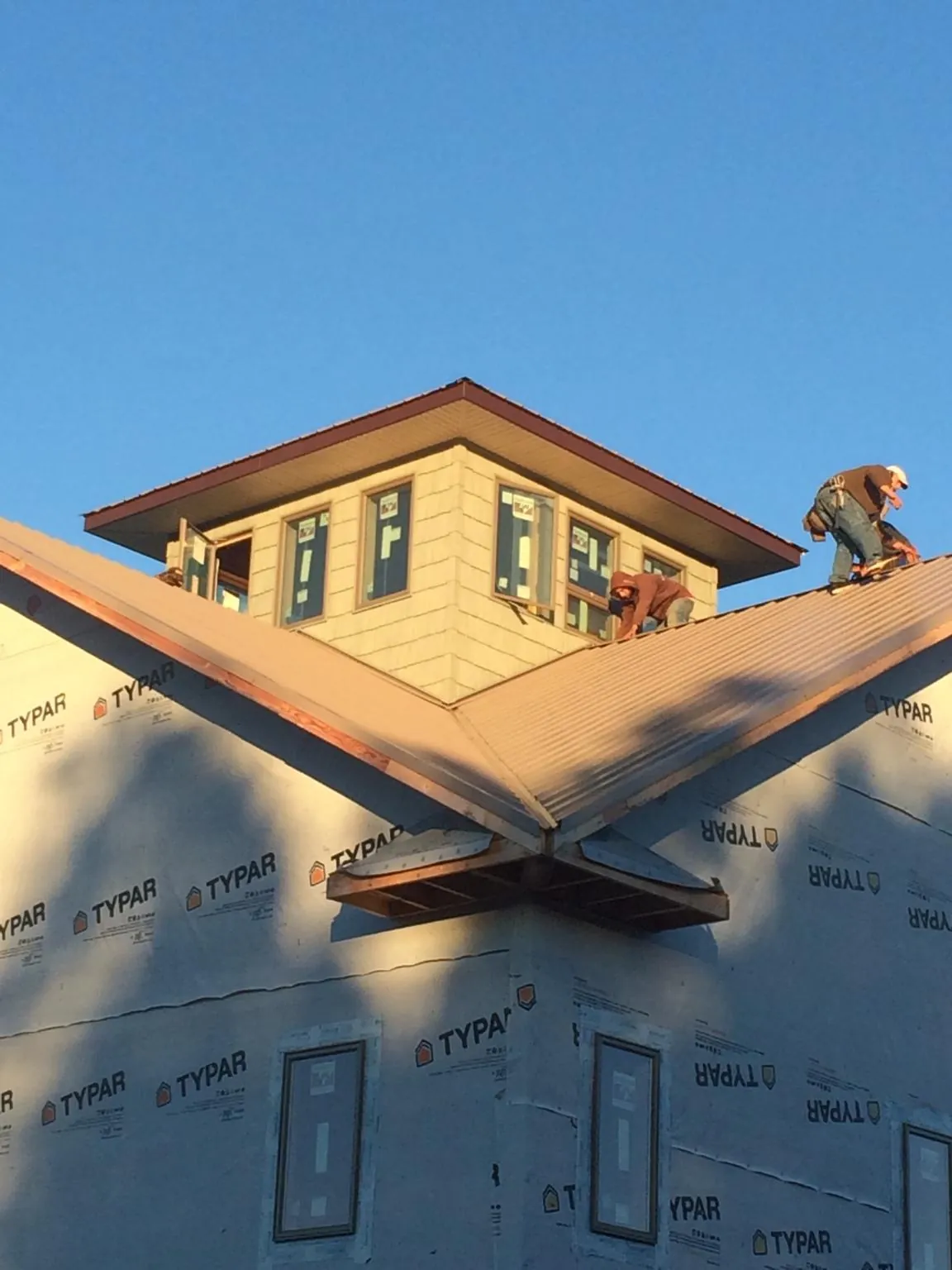 Roofers working around a rooftop cupola on a new metal roof at sunset — Roof Waterproofing in East Kingston by Roofing Brothers